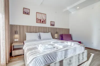 a bedroom with a bed and a purple chair at Adriatik Lux Apartments in Budva