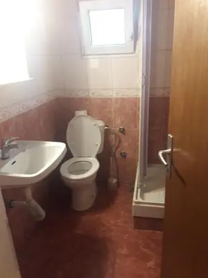a bathroom with a toilet and a sink and a window at Apartmani Bugarski in Rafailovici