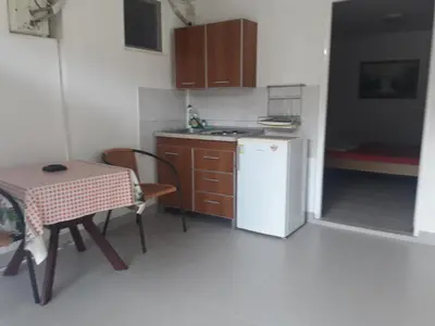 a small kitchen with a table and a white refrigerator at Apartmani Bugarski in Rafailovici