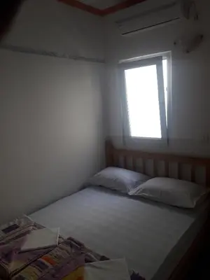 a small bedroom with a bed and a window at Apartmani Bugarski in Rafailovici