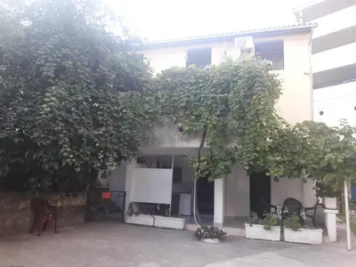 a white house with a bunch of trees in front of it at Apartmani Bugarski in Rafailovici