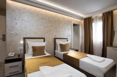 a hotel room with two beds and a desk at Hotel Fobra in Podgorica