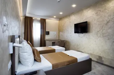 a hotel room with two beds and a flat screen tv at Hotel Fobra in Podgorica