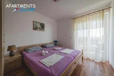 a bedroom with a bed with purple sheets and a window at Apartments South in Ulcinj