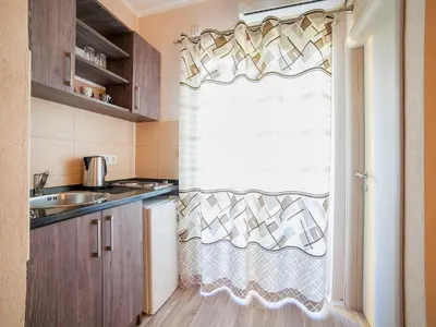 a kitchen with a window with a curtain and a sink at Pansion Nobel in Petrovac na Moru