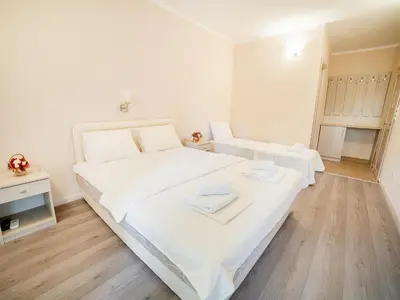 a bedroom with a large white bed with white sheets at Pansion Nobel in Petrovac na Moru