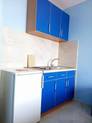 a kitchen with blue cabinets and a white refrigerator at Apartmani Lekovic Sutomore in Sutomore