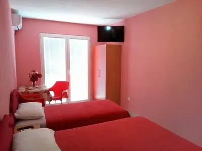 a red room with two beds and a table with a chair at Apartmani Lekovic Sutomore in Sutomore