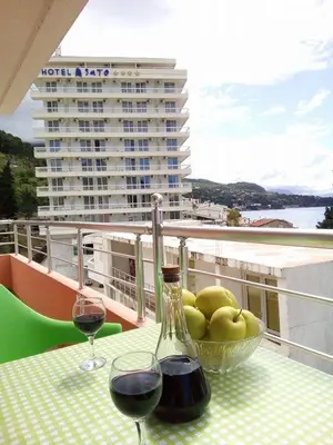 a table with two glasses of wine and a bowl of fruit at Apartmani Lekovic Sutomore in Sutomore