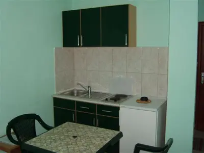 a kitchen with green cabinets and a sink and a table at Apartmani Lekovic Sutomore in Sutomore