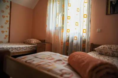 a bedroom with two beds and a window with curtains at LOVCEN4ME in Cetinje