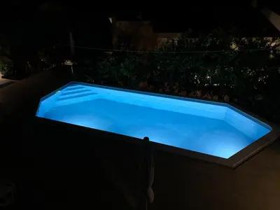 a large blue swimming pool at night at Reževići Apartments in Petrovac na Moru