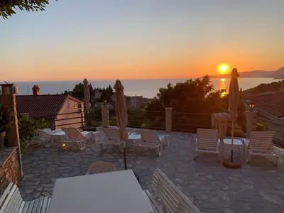 a sunset over a patio with chairs and umbrellas at Reževići Apartments in Petrovac na Moru