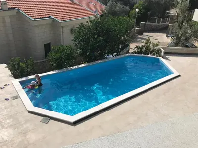 an overhead view of a swimming pool with a child in it at Reževići Apartments in Petrovac na Moru