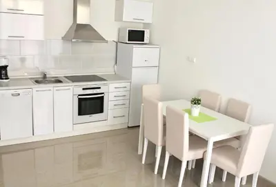 a kitchen with white cabinets and a table and chairs at Apartments Villa Milna 1 in Budva
