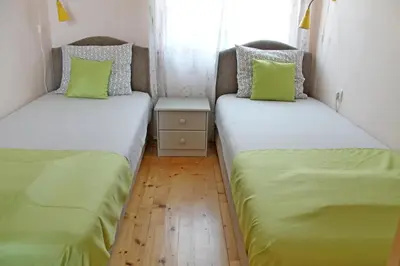 two beds in a small room with green pillows at Apartments Villa Milna 2 in Budva