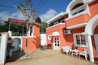 a orange building with chairs and a table on a patio at Apartments Kruna Jovanović in Sutomore
