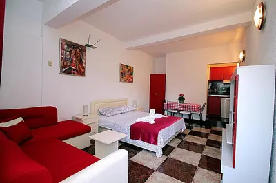 a bedroom with a red bed and a red couch at Apartments Kruna Jovanović in Sutomore