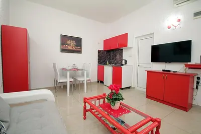 a living room with red cabinets and a kitchen with a table at Apartments Kruna Jovanović in Sutomore