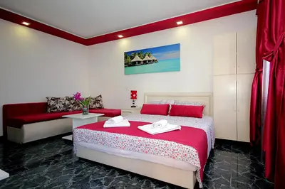 a bedroom with a red and white bed and a couch at Apartments Kruna Jovanović in Sutomore
