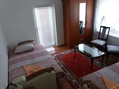 a room with two beds and a chair and a table at Zelena Maslina in Bar