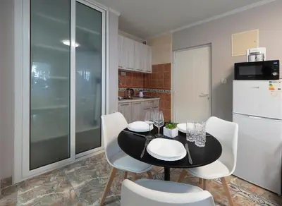 a kitchen with a black table and white chairs at Apartments Cataleya Przno in Sveti Stefan