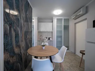 a kitchen with a wooden table and white chairs at Apartments Cataleya Przno in Sveti Stefan