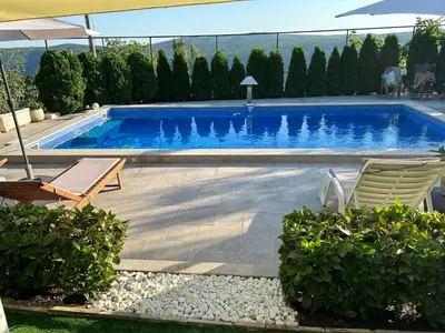 a swimming pool with two chairs and an umbrella at Vila Nikola in Bratesici