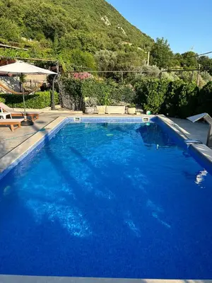 a large blue swimming pool with a mountain in the background at Vila Nikola in Bratesici