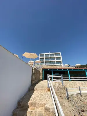 a stairs with an umbrella and a building at Apartments Komina in Utjeha