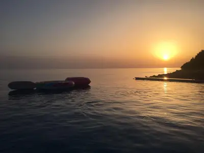 two canoes sitting on the water at sunset at Apartments Komina in Utjeha