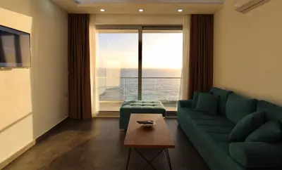 a living room with a green couch and a large window at Apartments Komina in Utjeha