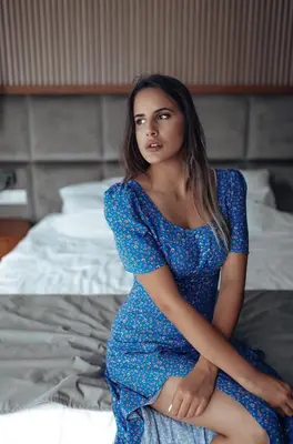 a woman in a blue dress sitting on a bed at Hotel Fagus by Aycon in Budva