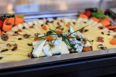 a tray of food with cheese and vegetables on it at Hotel Fagus by Aycon in Budva