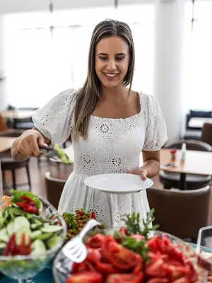 a woman holding a plate in front of a table of food at Hotel Fagus by Aycon in Budva