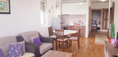 a living room with a couch and a table and a kitchen at Olimp Lux II in Budva