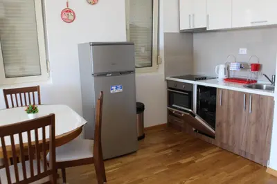 a small kitchen with a table and a refrigerator at Olimp Lux II in Budva