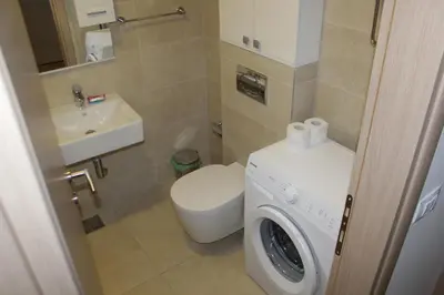 a bathroom with a toilet sink and a washing machine at Olimp Lux II in Budva