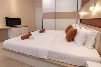 a bedroom with a white bed and a television at Hotel Butua Residence in Budva