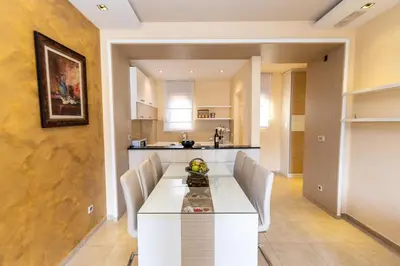 a kitchen and dining room with a white table and chairs at Hotel Butua Residence in Budva