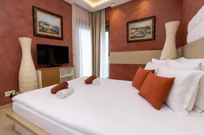 a bedroom with a large white bed with a television at Hotel Butua Residence in Budva