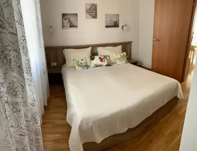 a bedroom with a bed with white sheets and pillows at Ive Lole Ribara 38 in Becici