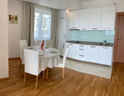 a white kitchen with a table and white chairs at Ive Lole Ribara 38 in Becici