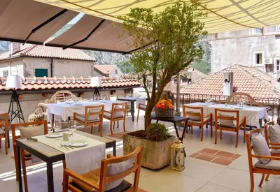 a restaurant with tables and chairs and a tree at Boutique Hotel Hippocampus in Kotor