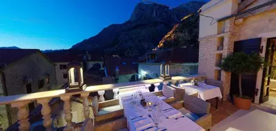 a balcony with tables and chairs and a mountain at Boutique Hotel Hippocampus in Kotor