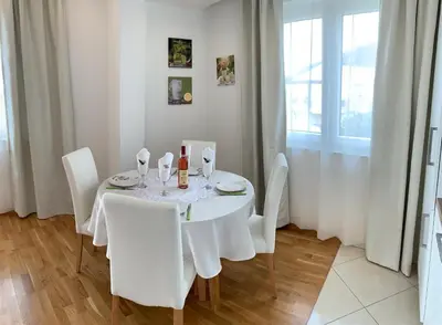 a white dining room table with white chairs and a window at The Magic Sea View Apartments in Budva