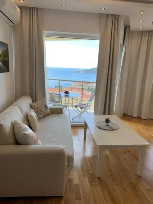 a living room with a couch and a table and a large window at The Magic Sea View Apartments in Budva