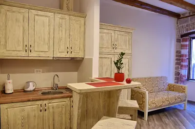 a kitchen with wooden cabinets and a sink and a chair at Apartments Kotor Old Town in Kotor