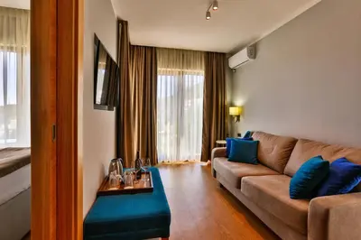 a living room with a brown couch and blue pillows at Hotel Lusso Mare by Aycon in Budva