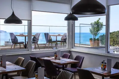 a restaurant with tables and chairs and a view of the ocean at Hotel Lusso Mare by Aycon in Budva